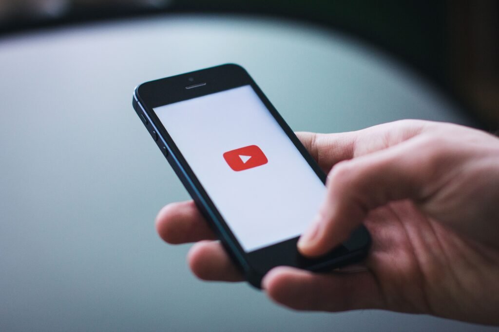 Hand holding a phone showing the YouTube app